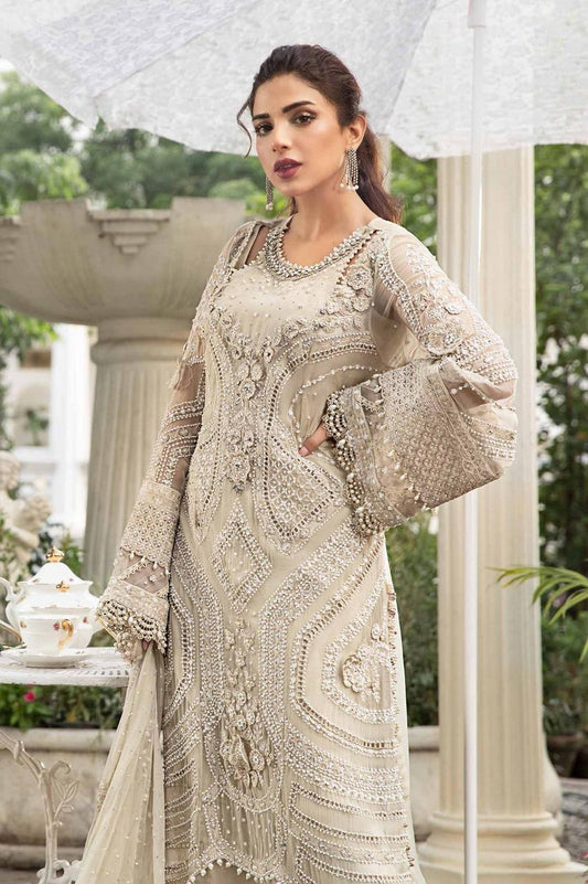 Woman wearing a intricately designed beige outfit with long sleeves in an outdoor setting.