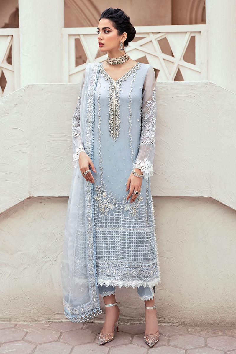 Woman wearing a light blue embroidered dress with a white dupatta against a neutral background