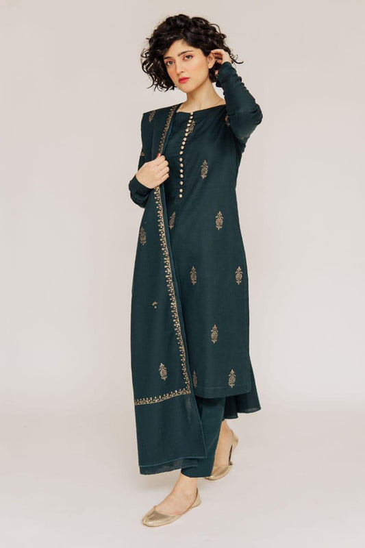 Woman wearing a dark green embroidered outfit on a light background