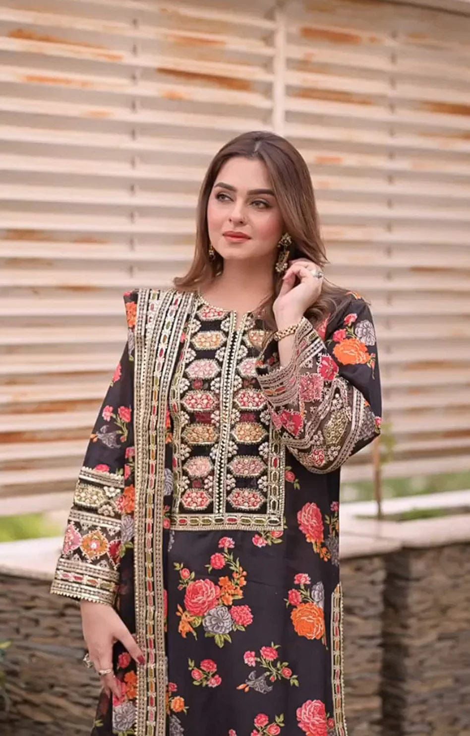 Woman wearing a black embroidered dress with floral patterns against a wooden background