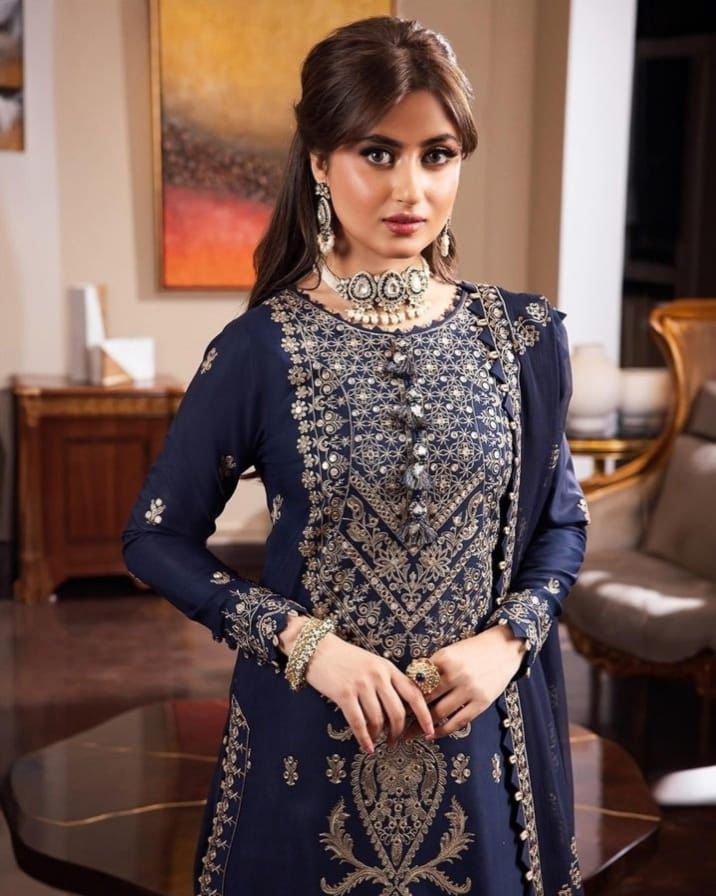 Woman wearing a navy blue embroidered outfit in an indoor setting