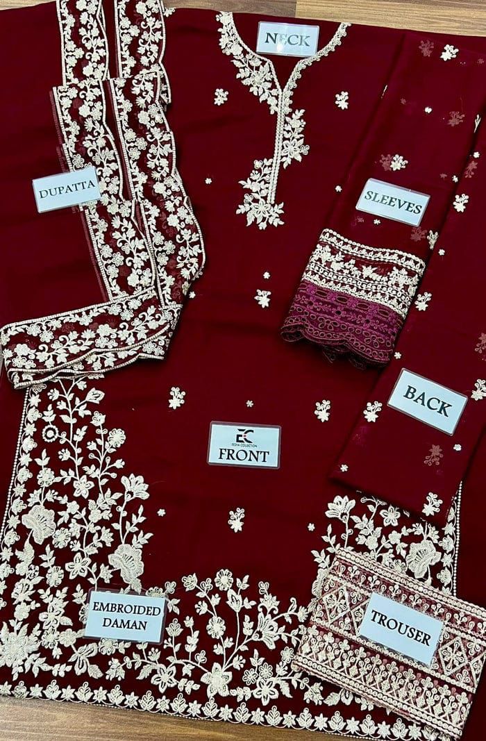 Maroon embroidered outfit with labels indicating parts of the garment on a wooden surface.