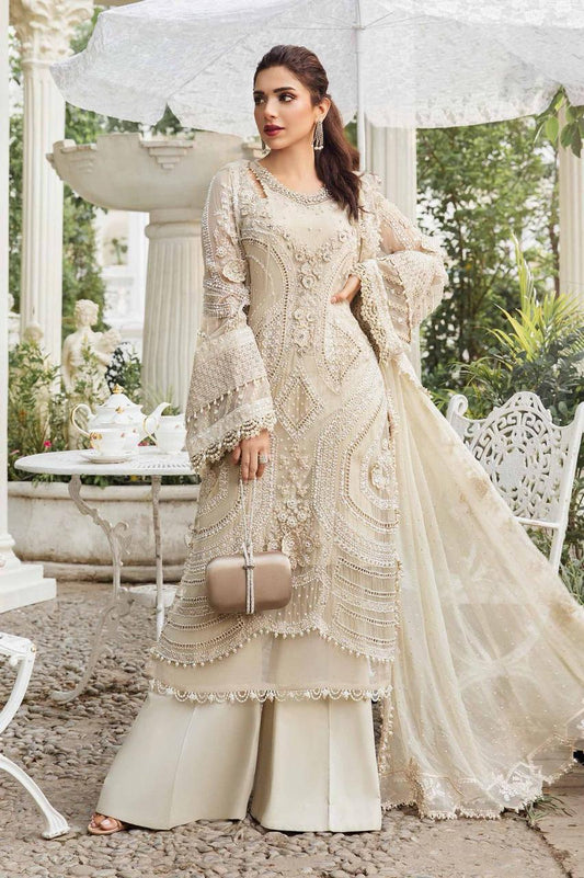 Woman in a cream embroidered traditional outfit standing in an elegant outdoor setting.