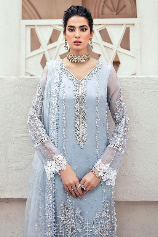 Woman wearing a light blue embroidered dress with a white background
