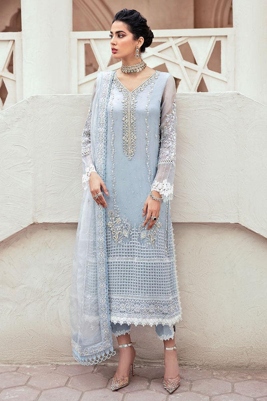Woman wearing a light blue embroidered dress with a white dupatta against a neutral background
