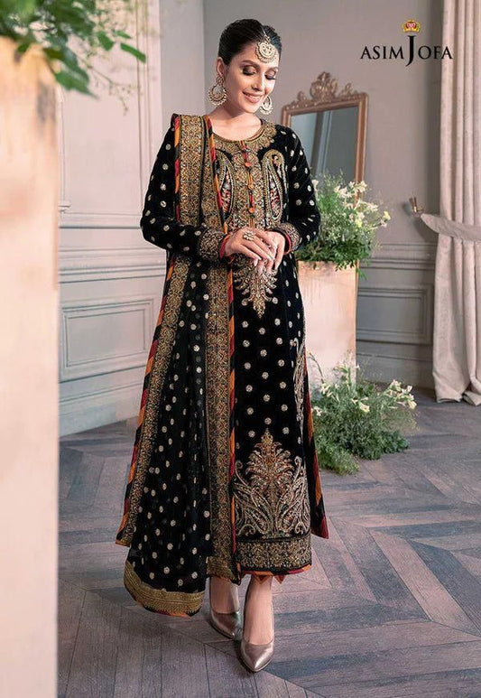Woman in a black and gold traditional outfit with 'Asim Jofa' branding in an elegant indoor setting.
