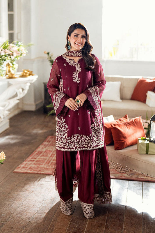 Woman in a maroon embroidered traditional outfit standing in a living room.