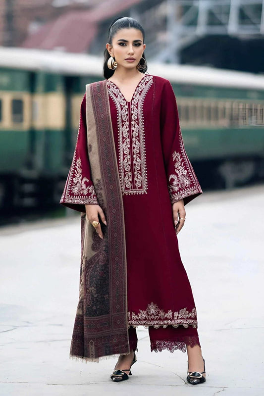 Woman in a burgundy embroidered outfit with a long scarf, standing outdoors.